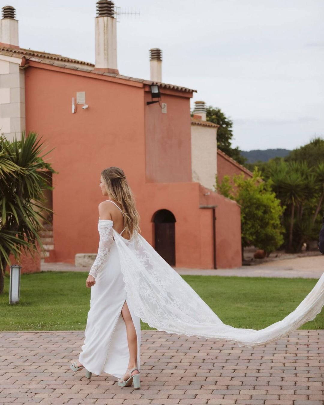 Anna de espaldas — capa de tul bordado al vuelo, finca catalana