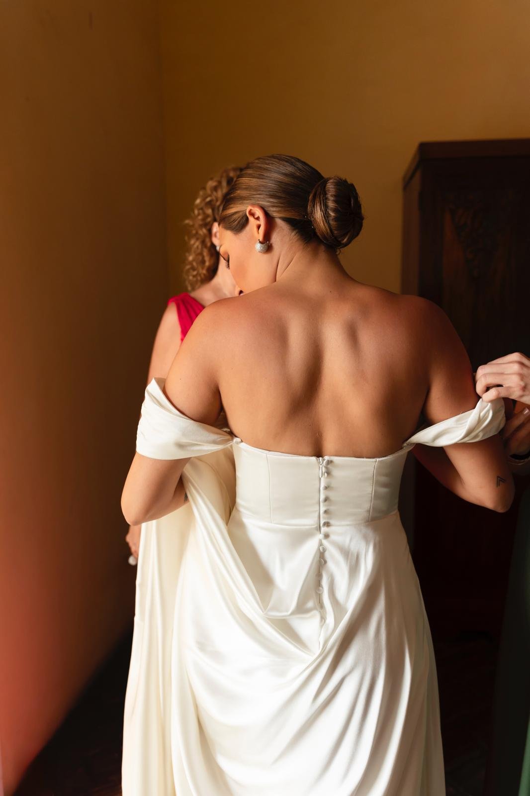 Detalle de la espalda del vestido con el drapeado del hombro cayendo mientras la visten