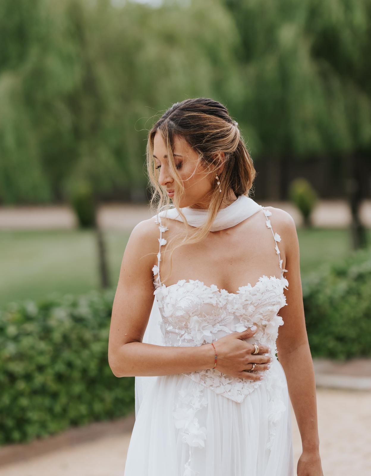 Detalle del corset de flores cosidas a mano sobre el cuerpo del vestido de novia de Claudia, con falda de tul, en los jardines de Mas Palau Blanes