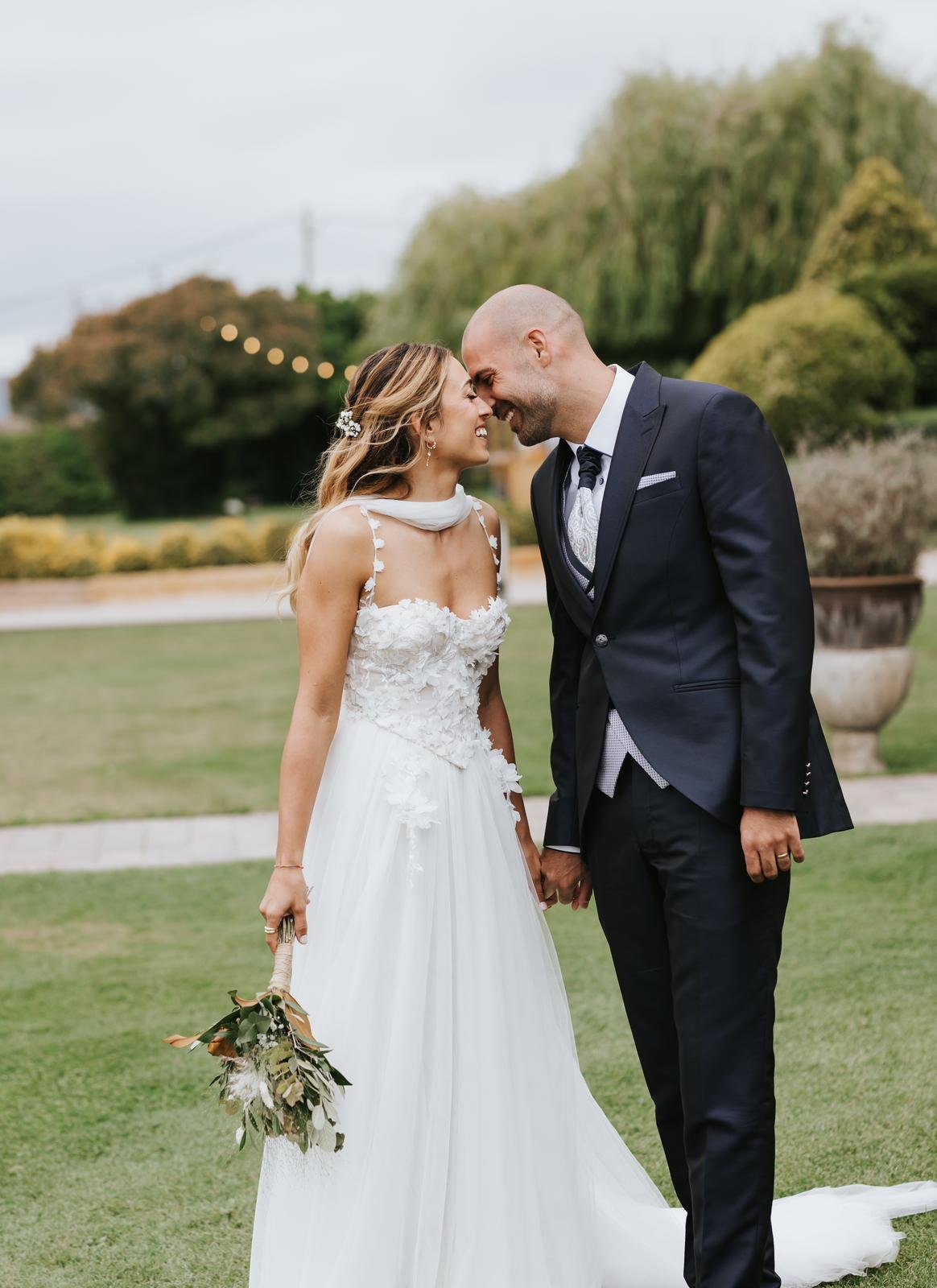 Claudia y su pareja en los jardines de la masía Mas Palau Blanes, vestido de novia con corset de flores cosidas a mano y falda de tul