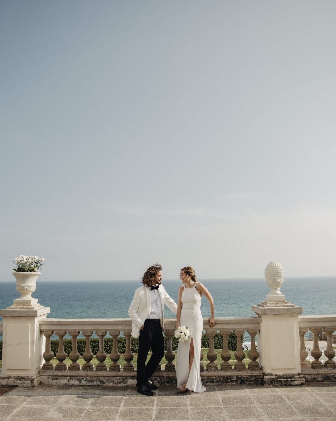 Vestido de novia de crepé con cuello halter sobre la terraza con vistas al Mediterráneo de Santa Romana