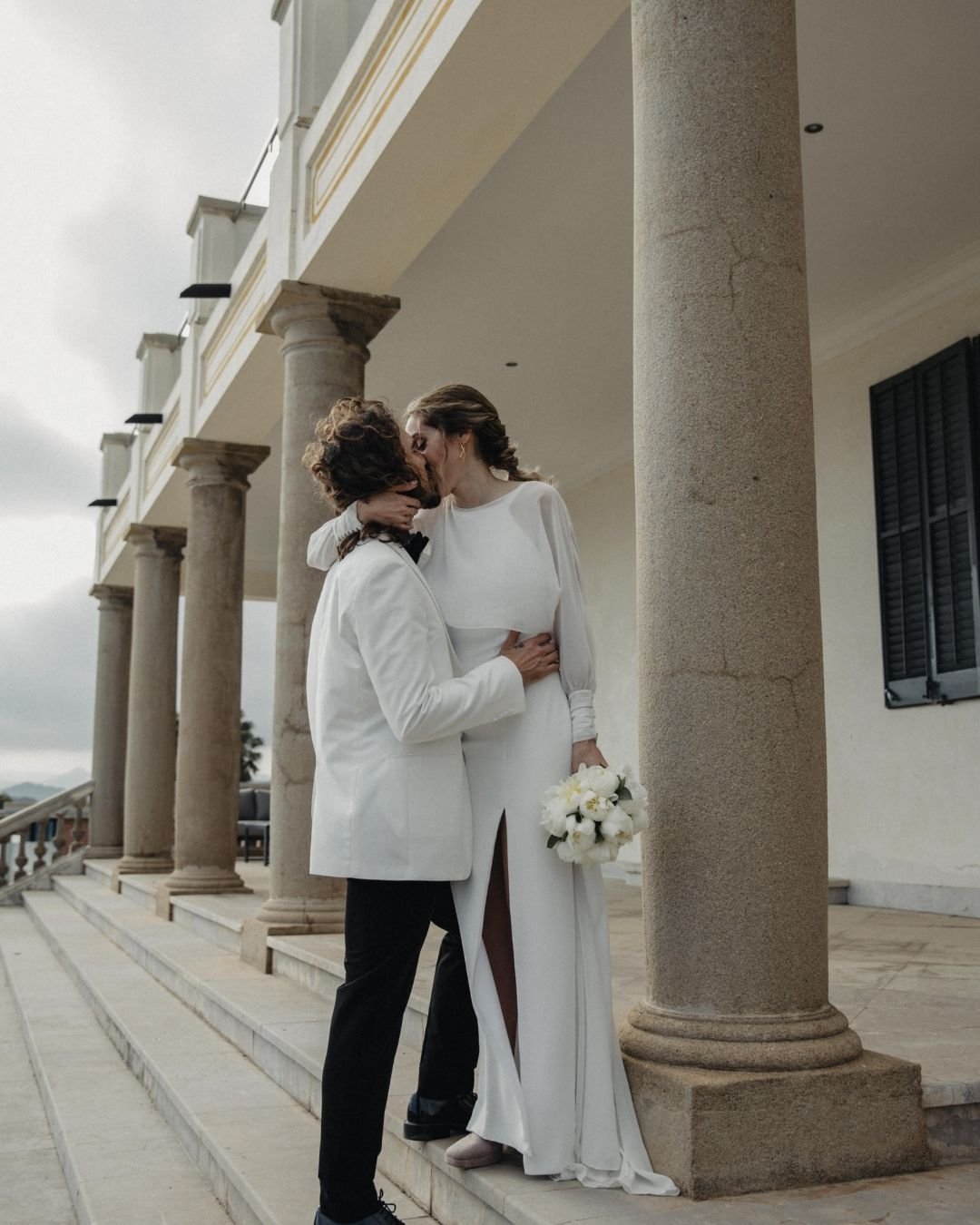 Gemma y su pareja entre las columnas de Santa Romana, chaqueta de gasa con puños drapeados sobre vestido de crepé