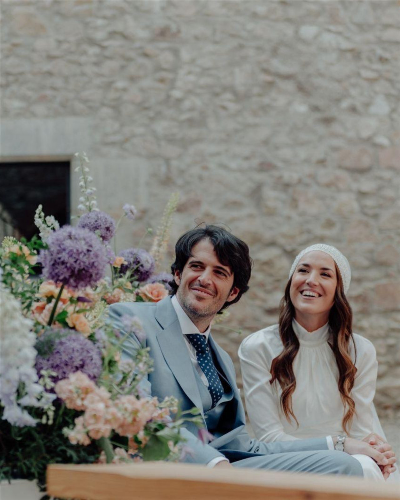 Gemma y su pareja durante la ceremonia con composición floral en tonos malva en el Monestir de Sant Salvi