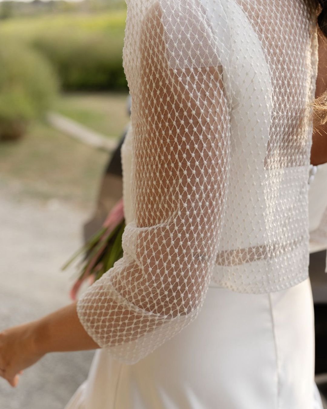 Detalle de la manga de tul bordado en motivo geométrico de la chaqueta del look de novia de Laura