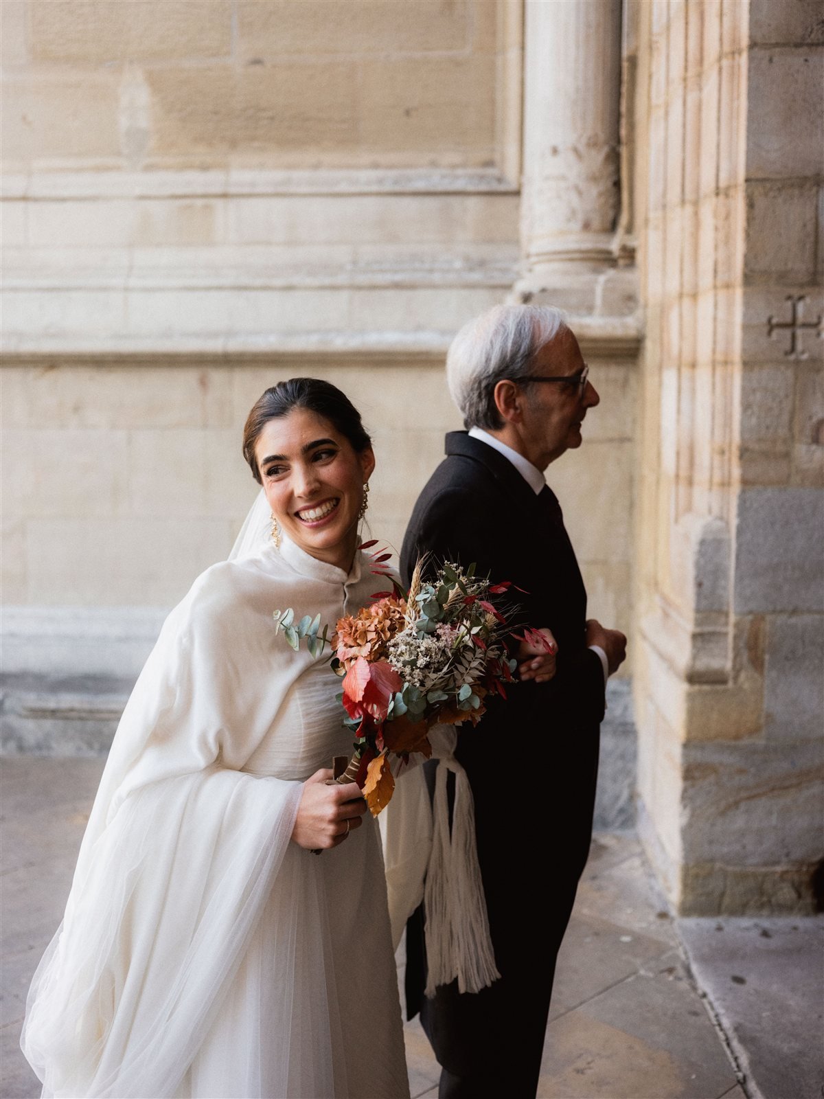 María entrando del brazo de su padre a la basílica con la capa de terciopelo de seda con cola, boda de invierno en el País Vasco