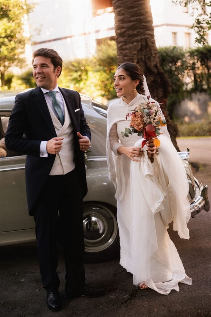 María y Carlos junto a un coche clásico con la capa de terciopelo de seda, boda de invierno en el País Vasco