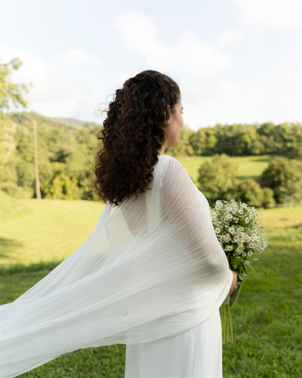 Espalda del look de novia de Marina: foulard de gasa plisada sobre vestido de gasa de seda, en los prados de la Masia El Collell