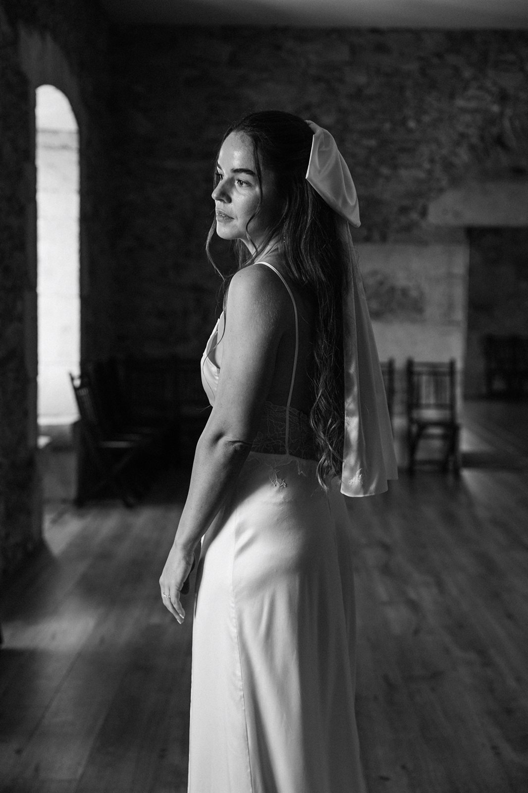 Nina con el vestido de satén de seda y lazo en el pelo, en un interior de piedra